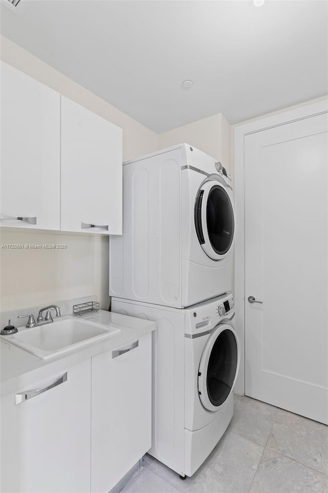 laundry area featuring sink, cabinets, and stacked washer and dryer