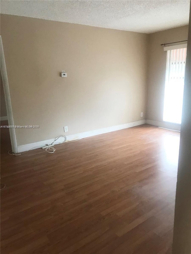 unfurnished room with dark wood-type flooring and a textured ceiling