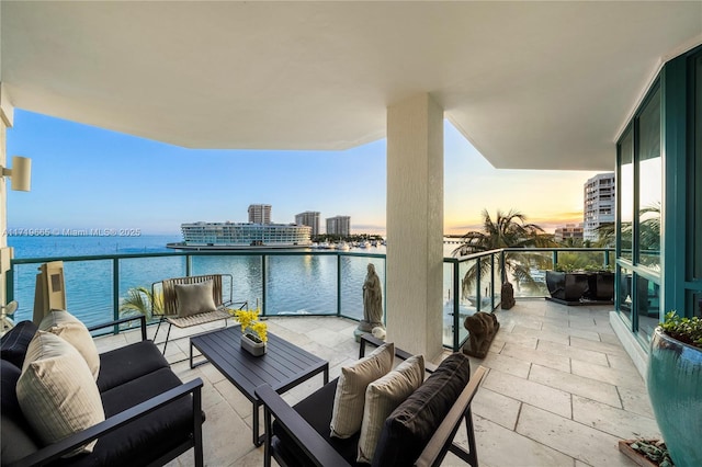 balcony at dusk with a water view and an outdoor hangout area