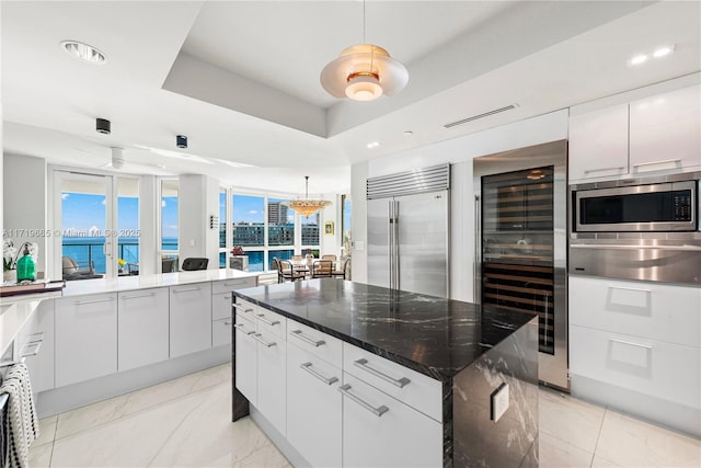 kitchen with built in appliances, decorative light fixtures, a water view, and white cabinets