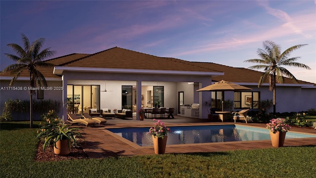 pool at dusk with an outdoor living space, a patio, and an outdoor kitchen