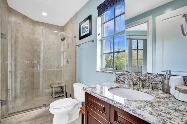 bathroom with vanity, toilet, and a shower with door