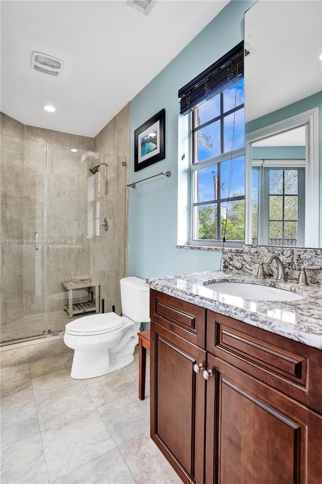 full bathroom with toilet, vanity, and a stall shower