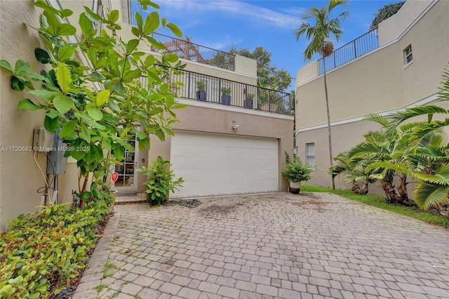 view of front of home featuring an attached garage, a balcony, decorative driveway, and stucco siding