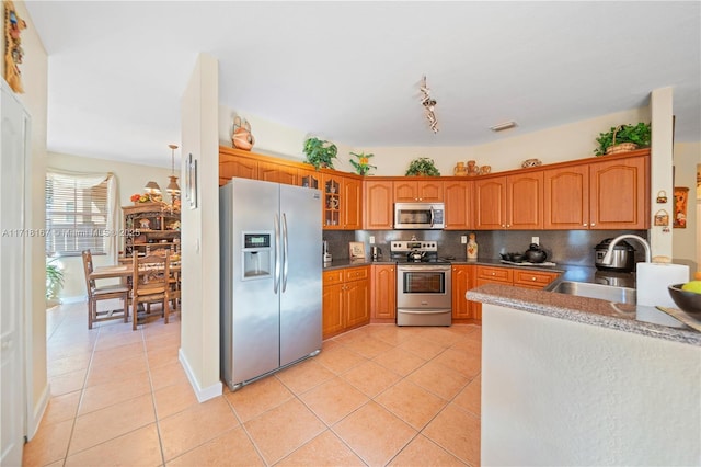 kitchen with light tile patterned floors, stainless steel appliances, tasteful backsplash, and sink