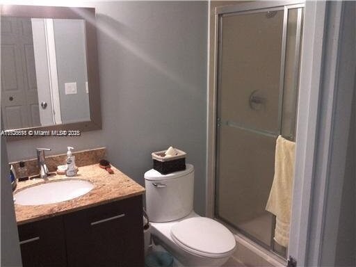 bathroom with vanity, toilet, and a shower with shower door