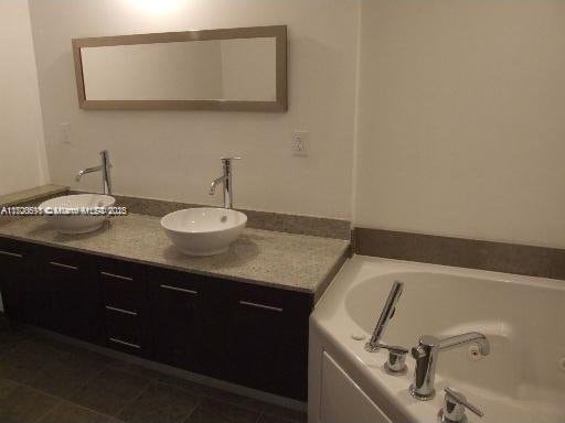 bathroom with tile patterned flooring, vanity, and a tub to relax in