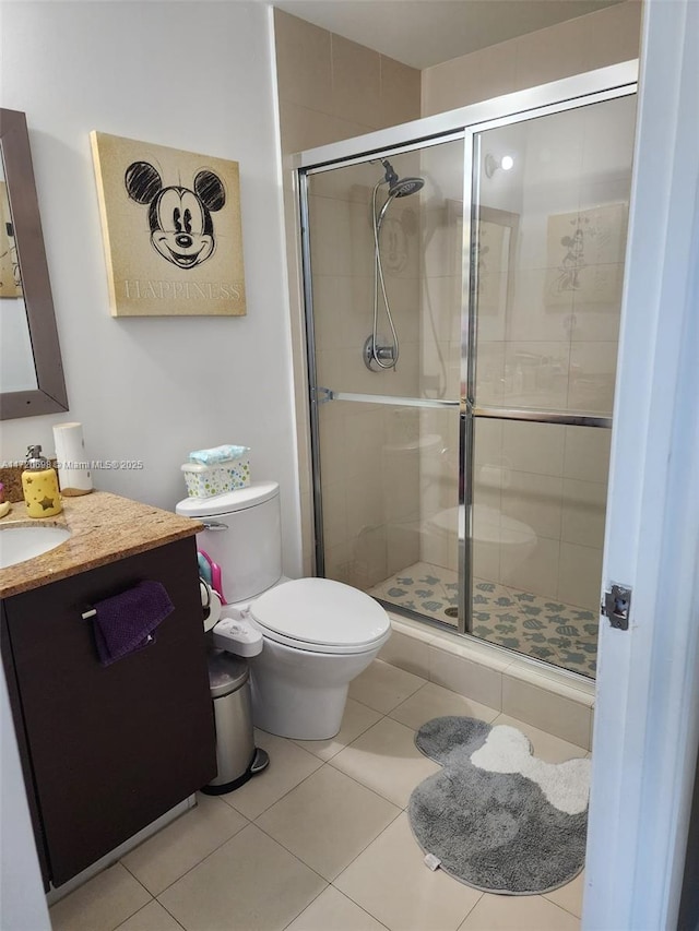 bathroom featuring tile patterned floors, a shower with door, vanity, and toilet