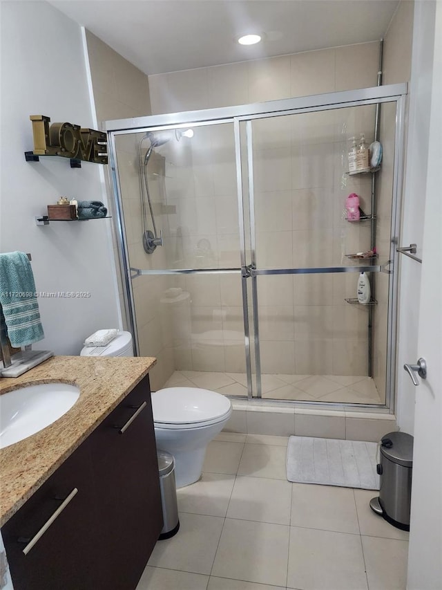 bathroom featuring tile patterned floors, vanity, toilet, and a shower with shower door