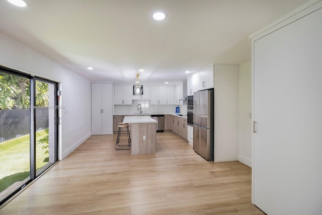 kitchen featuring white cabinets, a center island, a breakfast bar area, and stainless steel appliances