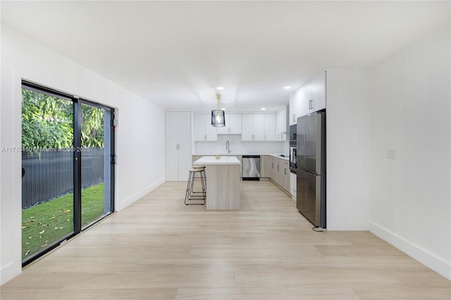 kitchen featuring white cabinets, sink, appliances with stainless steel finishes, a kitchen island, and a breakfast bar area