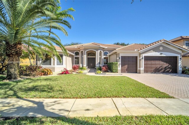 mediterranean / spanish house featuring a garage and a front lawn