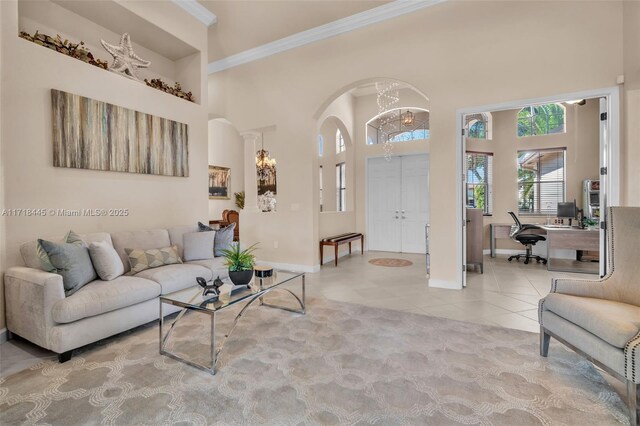 living room with crown molding, light tile patterned flooring, a high ceiling, and a notable chandelier