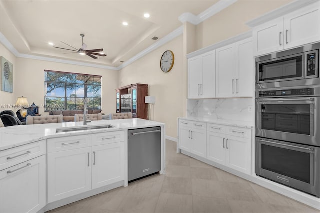 kitchen featuring a raised ceiling, sink, appliances with stainless steel finishes, tasteful backsplash, and white cabinetry