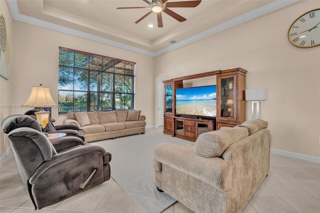 living room featuring ceiling fan, a raised ceiling, light tile patterned floors, and crown molding