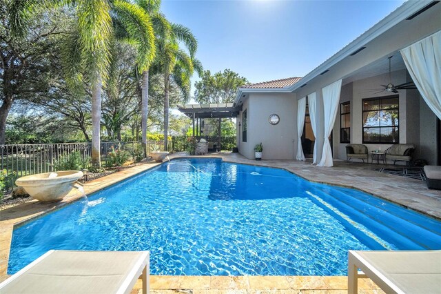 view of swimming pool featuring pool water feature, ceiling fan, and a patio area