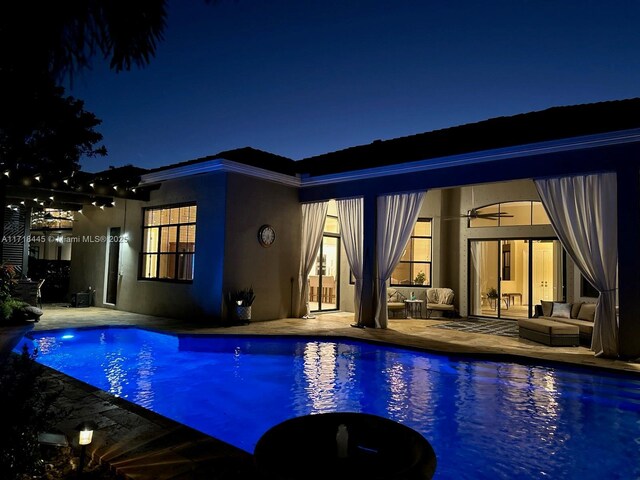 pool at twilight featuring an outdoor living space and a patio area