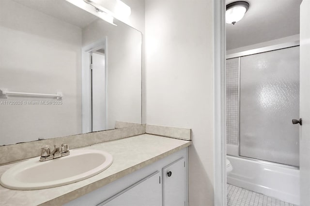 full bathroom with combined bath / shower with glass door, vanity, tile patterned flooring, and toilet