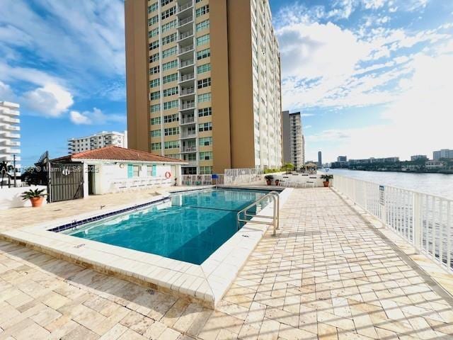 view of pool featuring a water view and a patio area