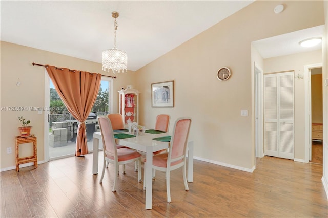 dining area with light hardwood / wood-style flooring, vaulted ceiling, and a notable chandelier