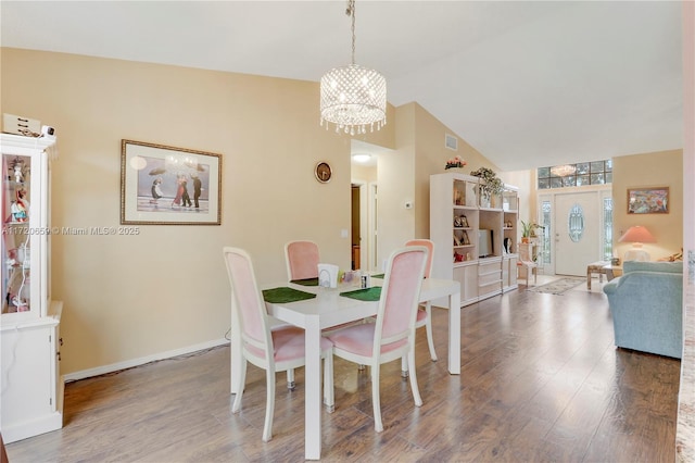 dining space featuring hardwood / wood-style floors, lofted ceiling, and an inviting chandelier