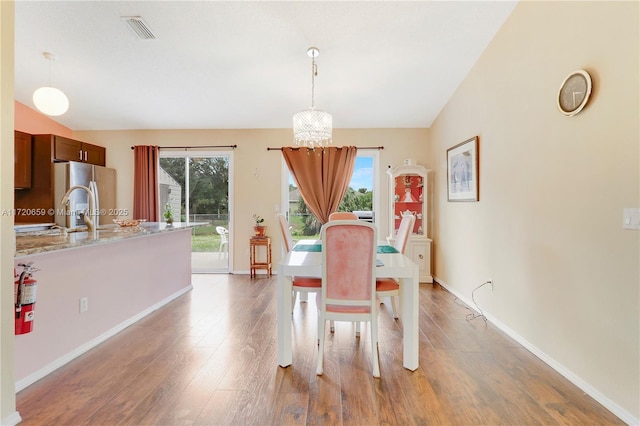 dining space featuring plenty of natural light, light hardwood / wood-style floors, vaulted ceiling, and an inviting chandelier