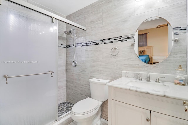 bathroom with vanity, toilet, a shower with door, and tile walls