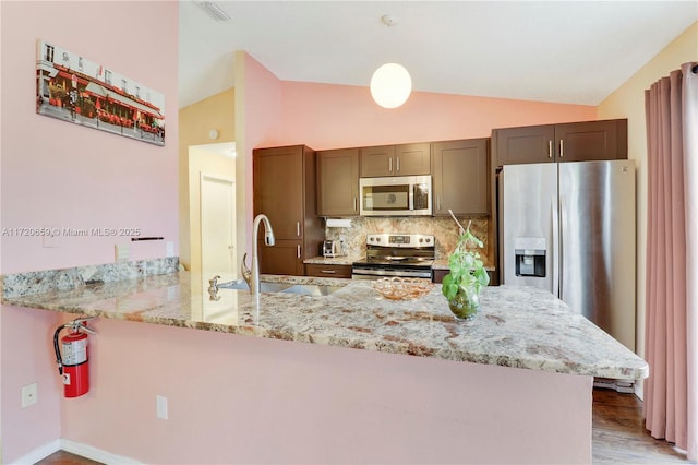 kitchen with lofted ceiling, sink, tasteful backsplash, kitchen peninsula, and stainless steel appliances