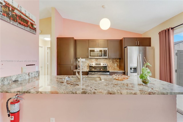 kitchen featuring hanging light fixtures, stainless steel appliances, backsplash, kitchen peninsula, and vaulted ceiling