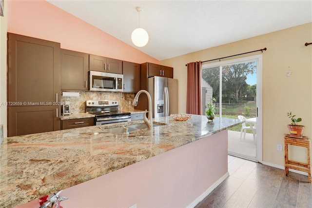 kitchen featuring sink, stainless steel appliances, tasteful backsplash, light stone counters, and decorative light fixtures