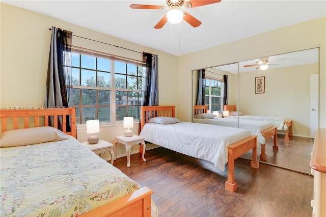 bedroom featuring multiple windows, dark hardwood / wood-style flooring, a closet, and ceiling fan