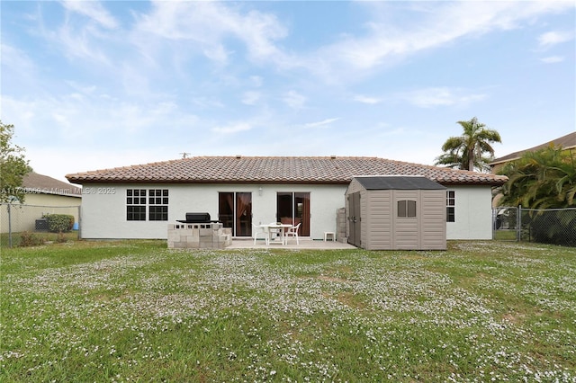 rear view of property with a patio area, a yard, and a storage unit