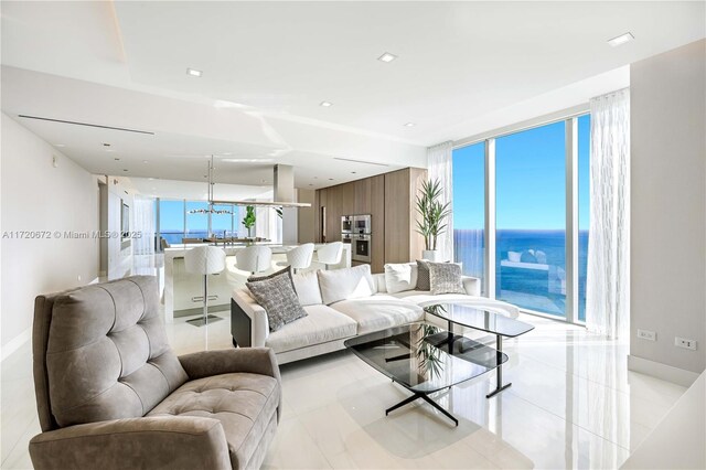 living room featuring a water view, a wall of windows, wooden walls, and light tile patterned flooring