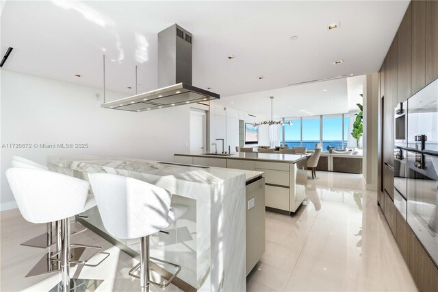 kitchen with floor to ceiling windows, a large island, a notable chandelier, decorative light fixtures, and island range hood