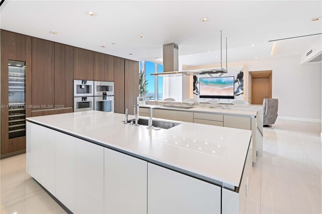 kitchen featuring white cabinetry, double oven, a large island, and sink