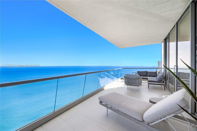 balcony with an outdoor living space and a water view