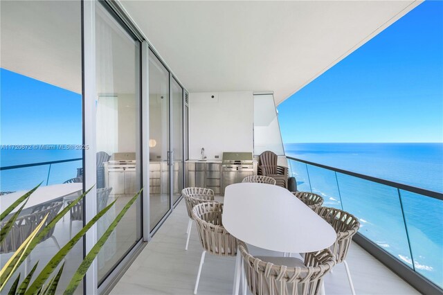 balcony with a grill, area for grilling, a water view, and sink