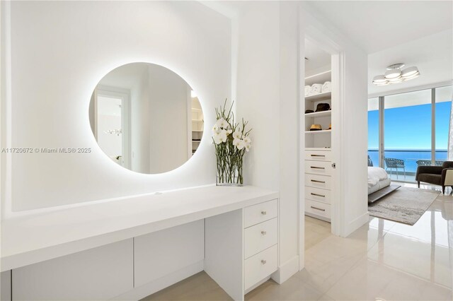 bathroom with tile patterned floors, a water view, and a wall of windows