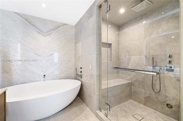 bathroom featuring tile patterned flooring, separate shower and tub, and tile walls