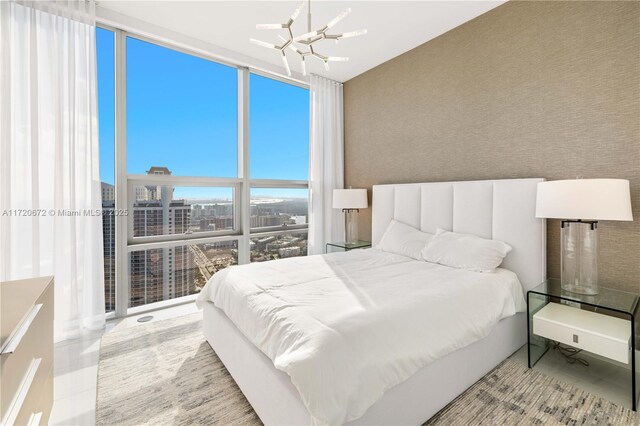 bedroom featuring a notable chandelier, a wall of windows, and multiple windows