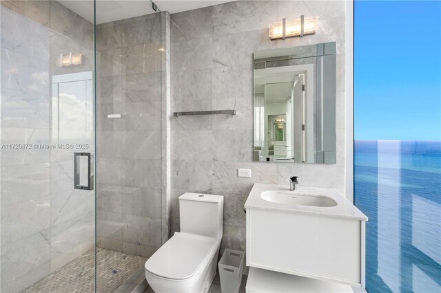 bathroom with vanity, a water view, toilet, tile walls, and a shower with shower door