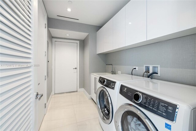 laundry area featuring cabinets, separate washer and dryer, light tile patterned flooring, and sink