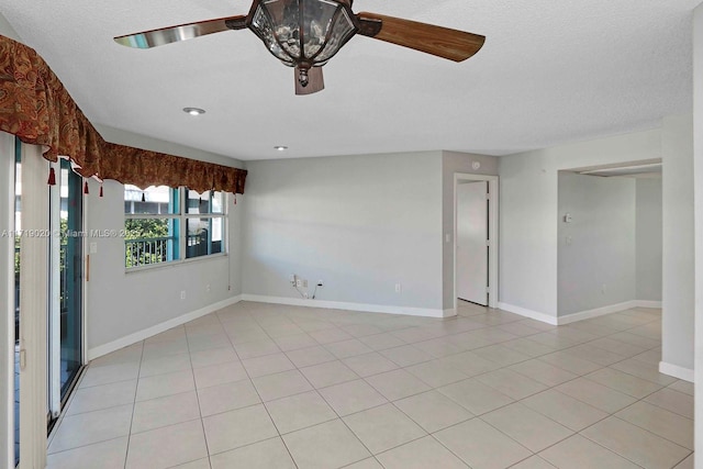 spare room featuring ceiling fan, light tile patterned floors, and a textured ceiling