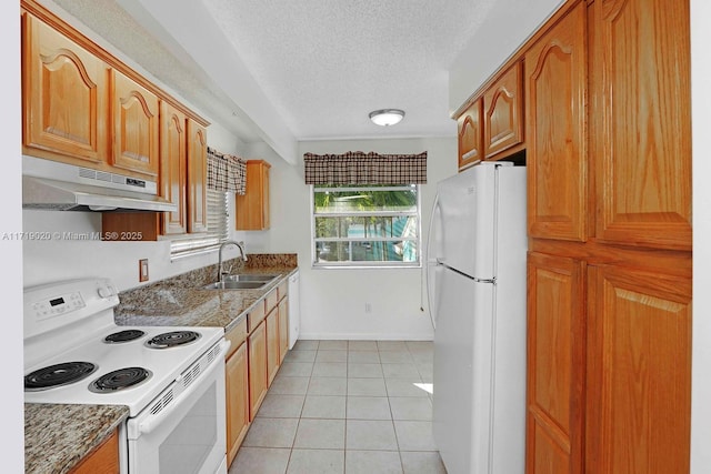 kitchen with white appliances, dark stone counters, sink, light tile patterned floors, and a textured ceiling