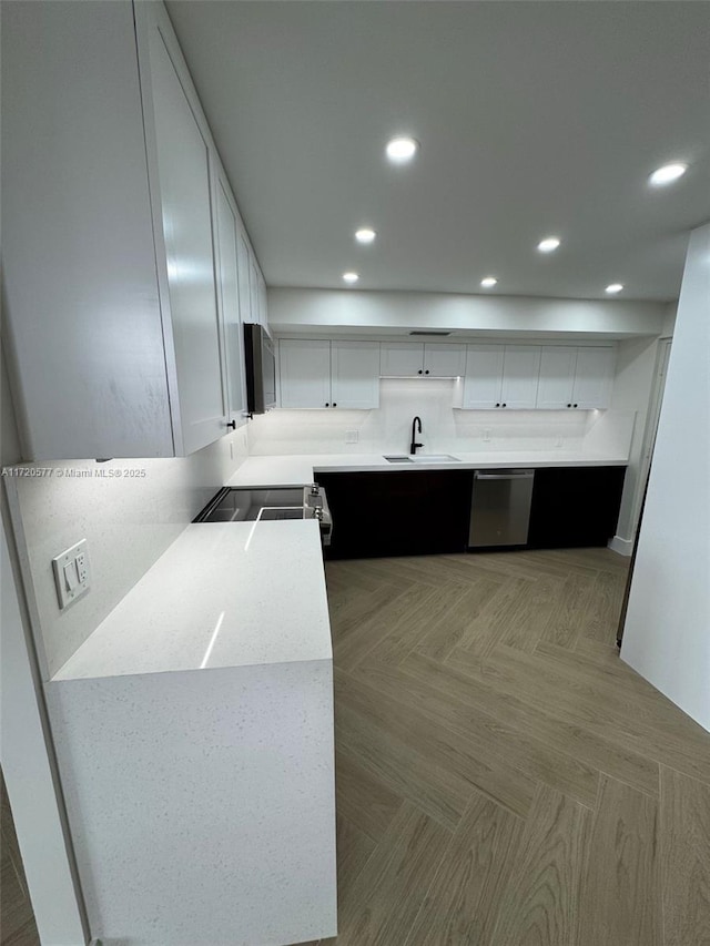 kitchen with white cabinetry, sink, dishwasher, and range