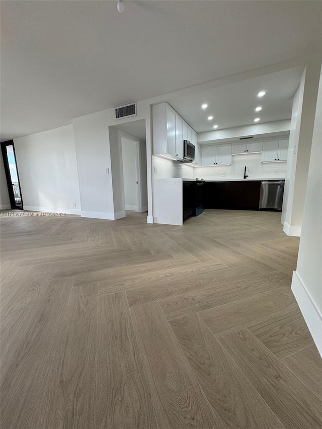 unfurnished living room featuring light parquet flooring and sink