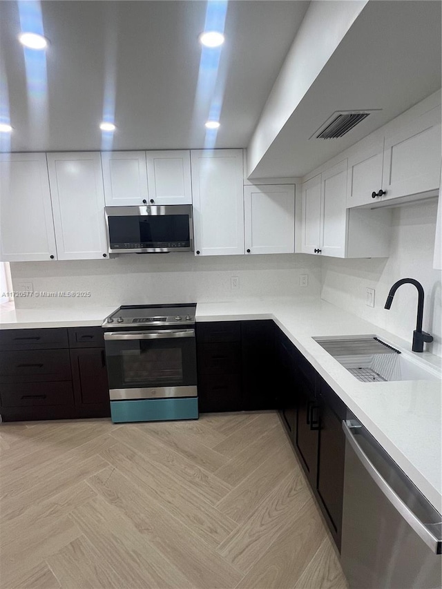 kitchen with stainless steel appliances, white cabinetry, and sink