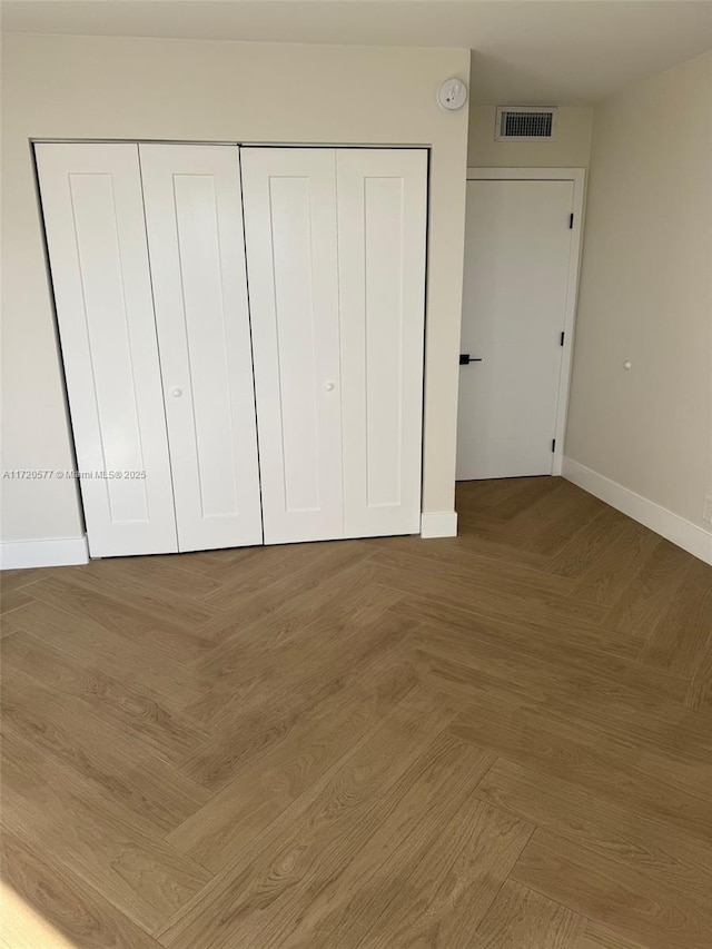 unfurnished bedroom featuring parquet flooring and a closet