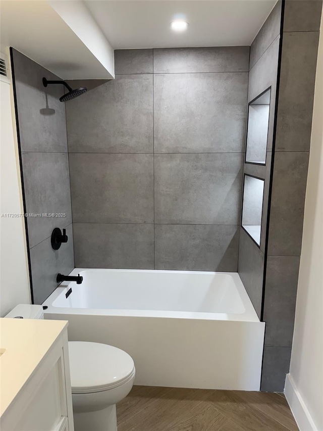 full bathroom with toilet, vanity, wood-type flooring, and tiled shower / bath