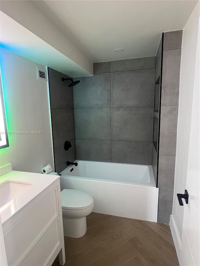 full bathroom with hardwood / wood-style flooring, tiled shower / bath combo, toilet, and vanity